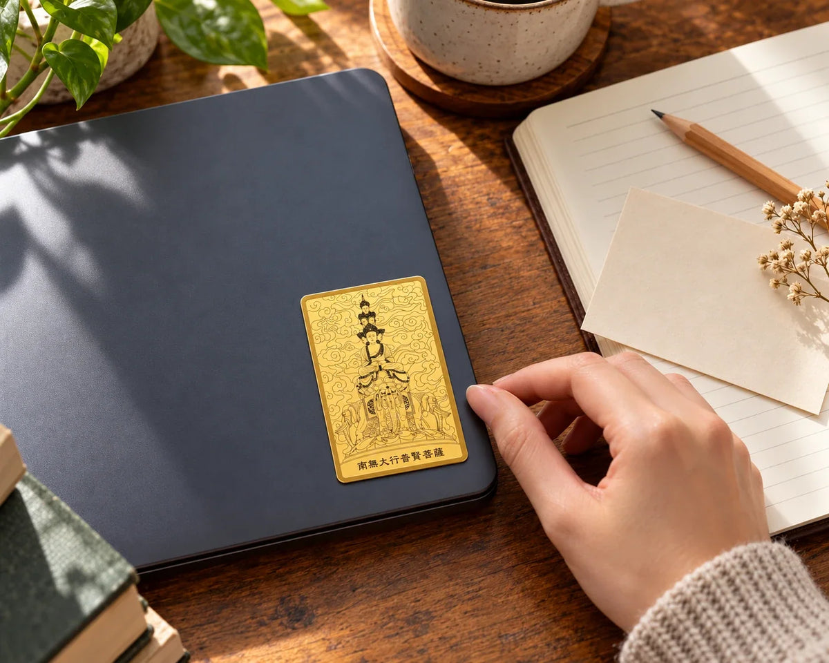 Samantabhadra gold sticker on a notebook beside a writing pad.