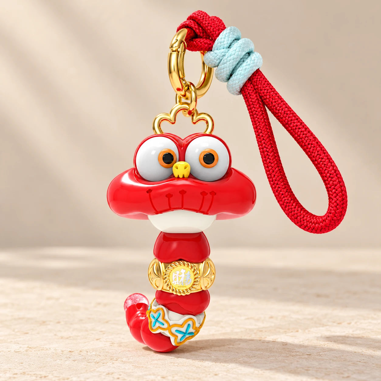 Fortune Mascot hanging charm with its full red character head, elongated segmented body and hanging cord