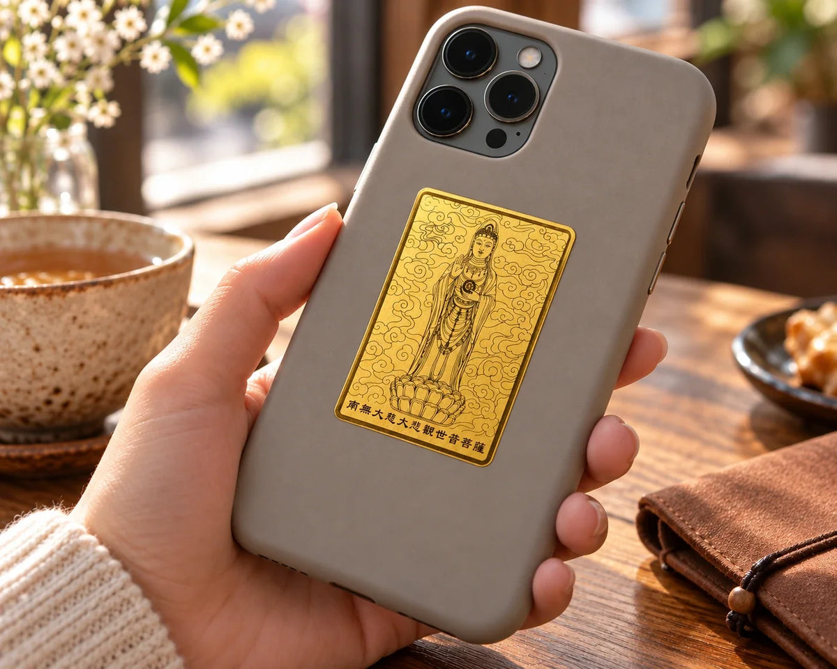 Guanyin gold phone sticker on a phone case held in one hand.