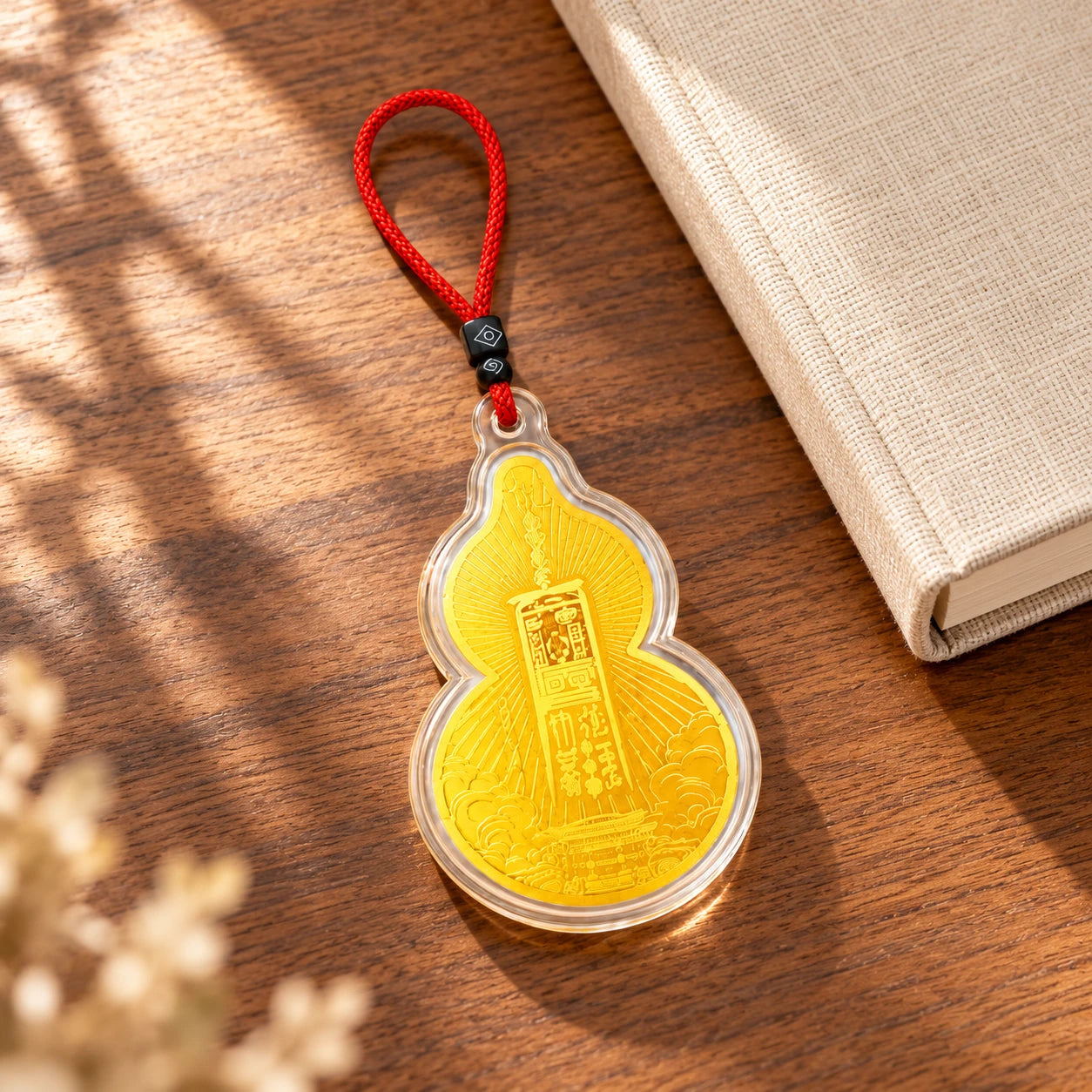 Complete gold-toned Wudang charm and red cord on a warm desk beside a closed cream notebook