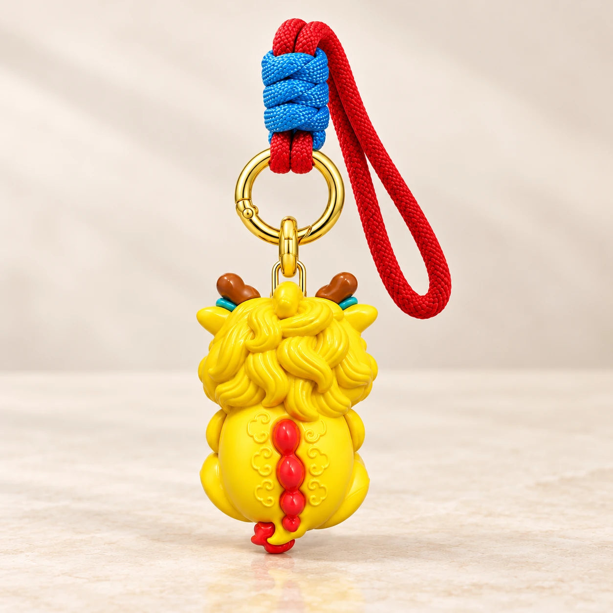 Single rear view of the Dragon Charm with sculpted yellow mane, red back details and complete cord
